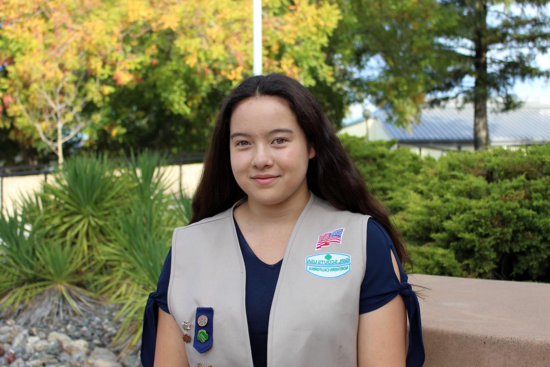 Student Nakyla Stolp sits at a bench wearing her scouting vest